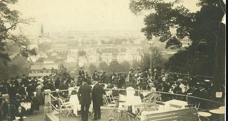 Fotografi från år 1910. Fler personer är samlade och tittar ut över Jönköping från restaurang Stugans uteservering. 